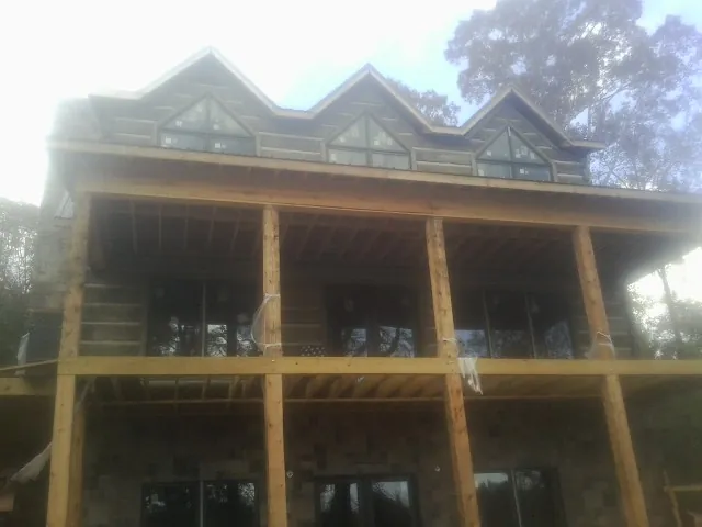 Dormers and porch framing on a large log home under construction — Roof Coating work by our crew in Grand River