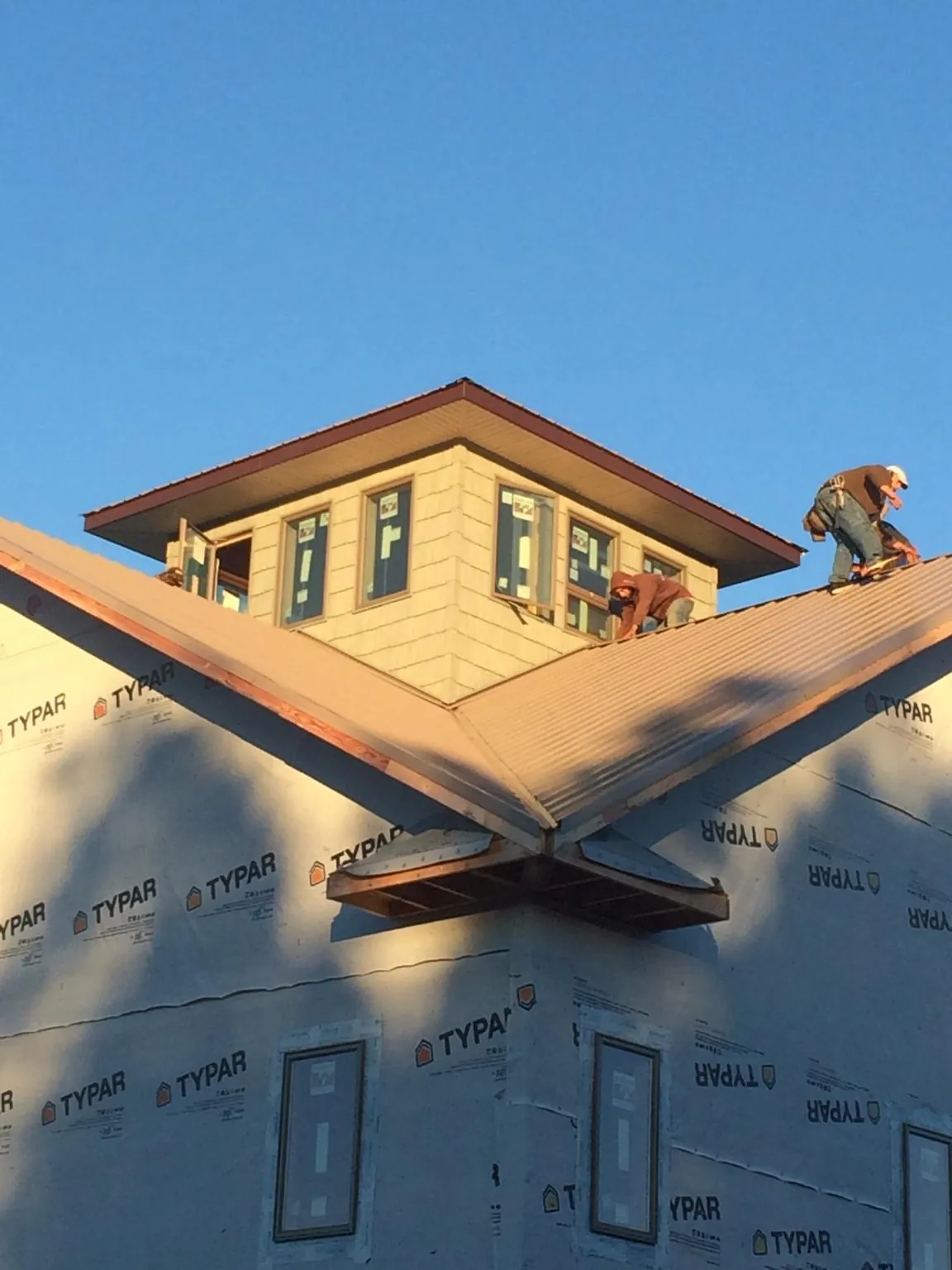 Roofers working around a rooftop cupola on a new metal roof at sunset — Roof Waterproofing in Grand River by Roofing Brothers